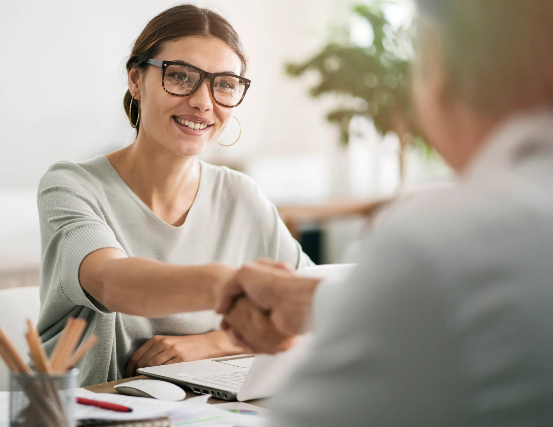 Vrouw schudt hand van aangenomen persoon bij nieuwe baan