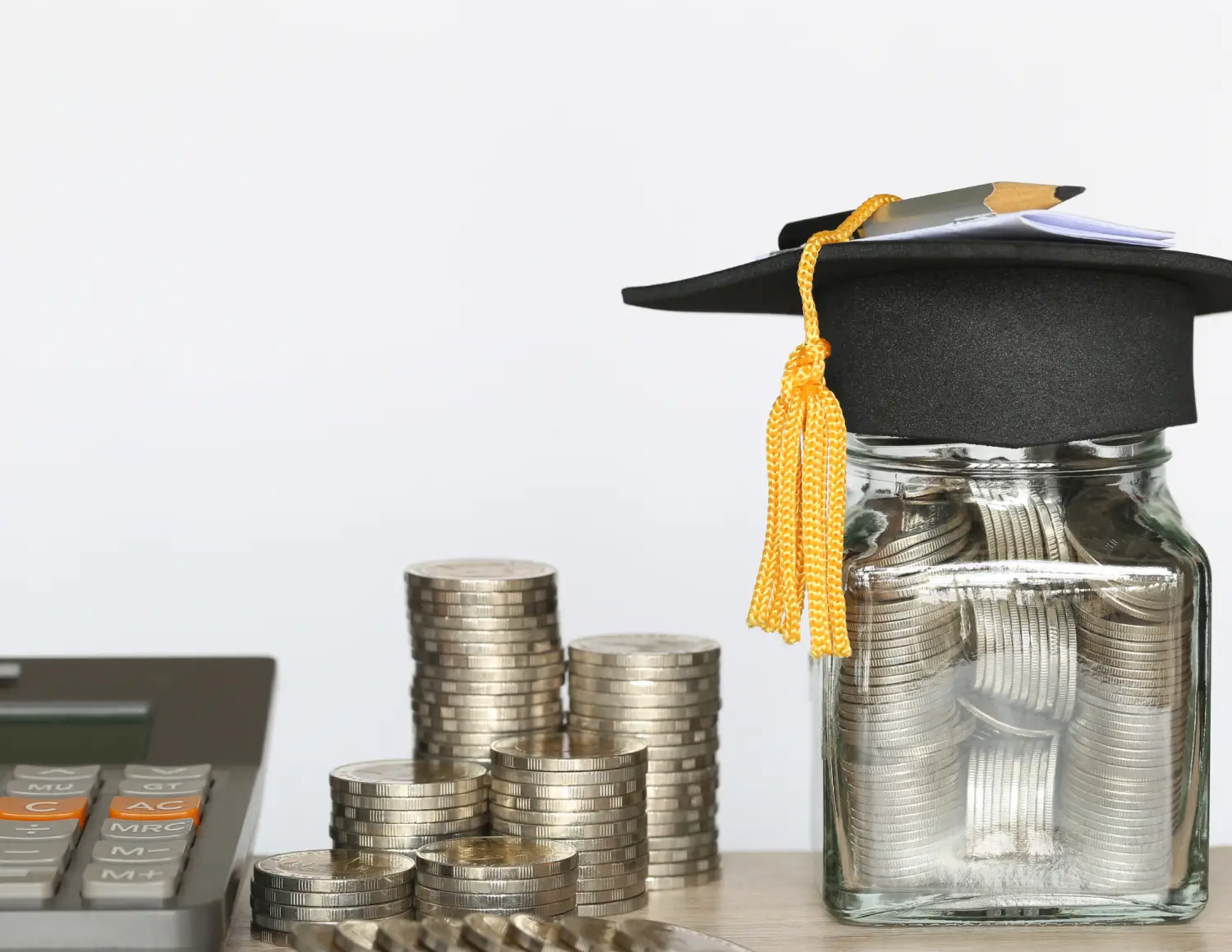 Geldpotje met studentenhoedje en rekenmachine en muntgeld