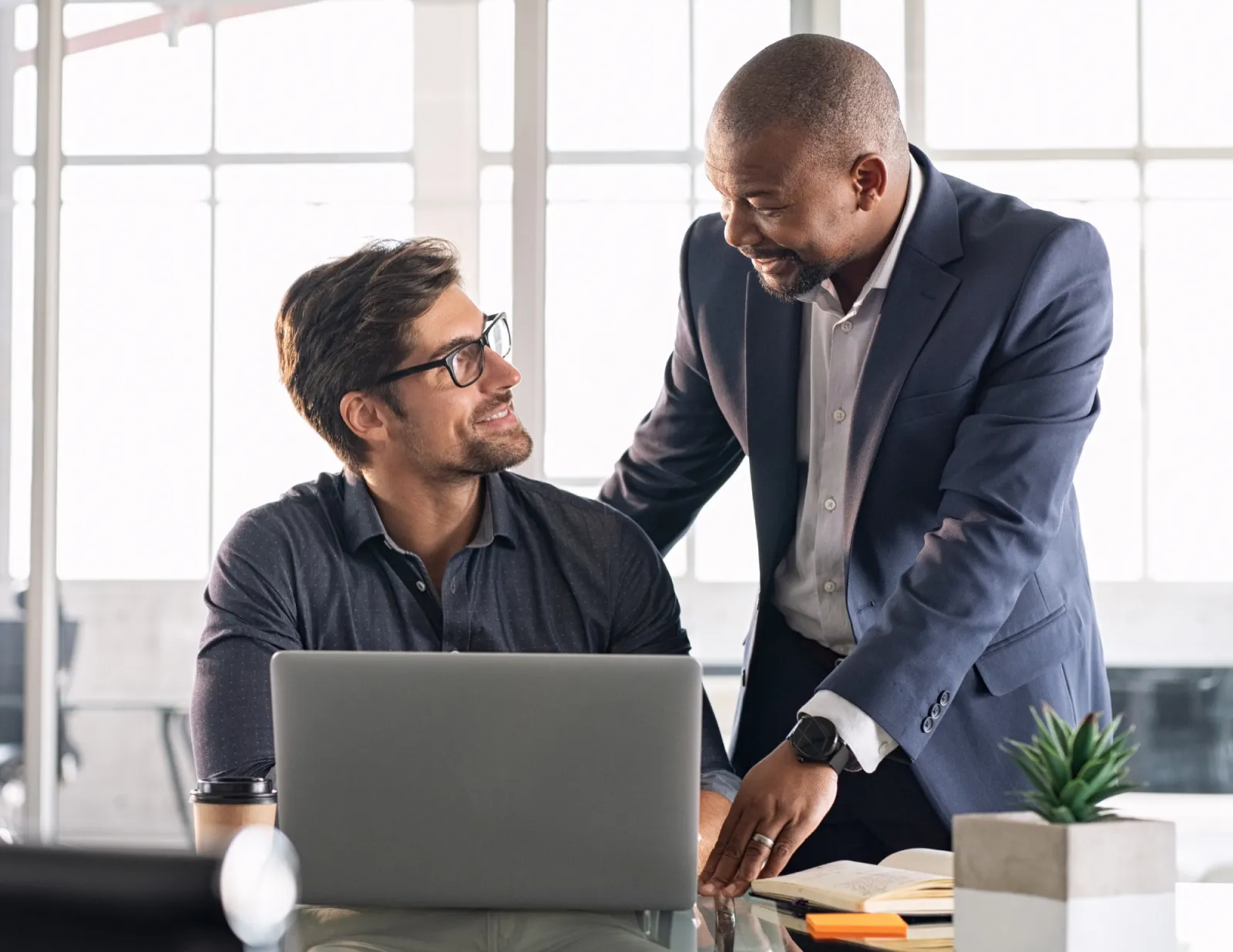 Werknemer en werkgever staan samen achter laptop aan het werk