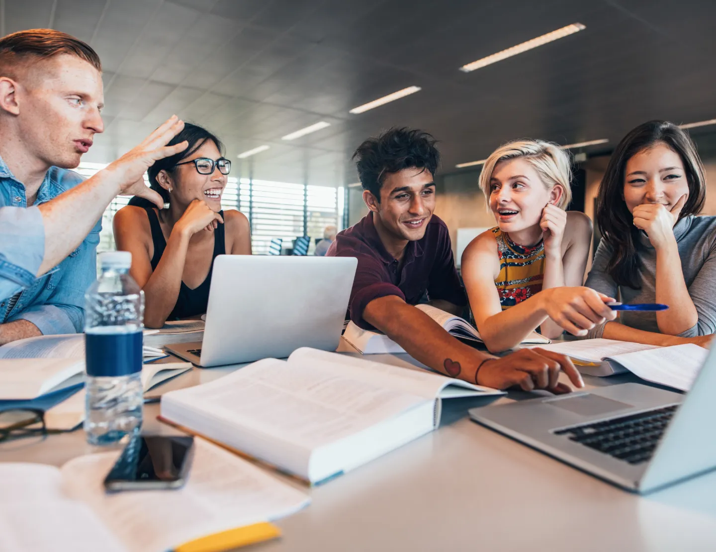 Studeren aan het studeren aan een tafel met boeken en laptops