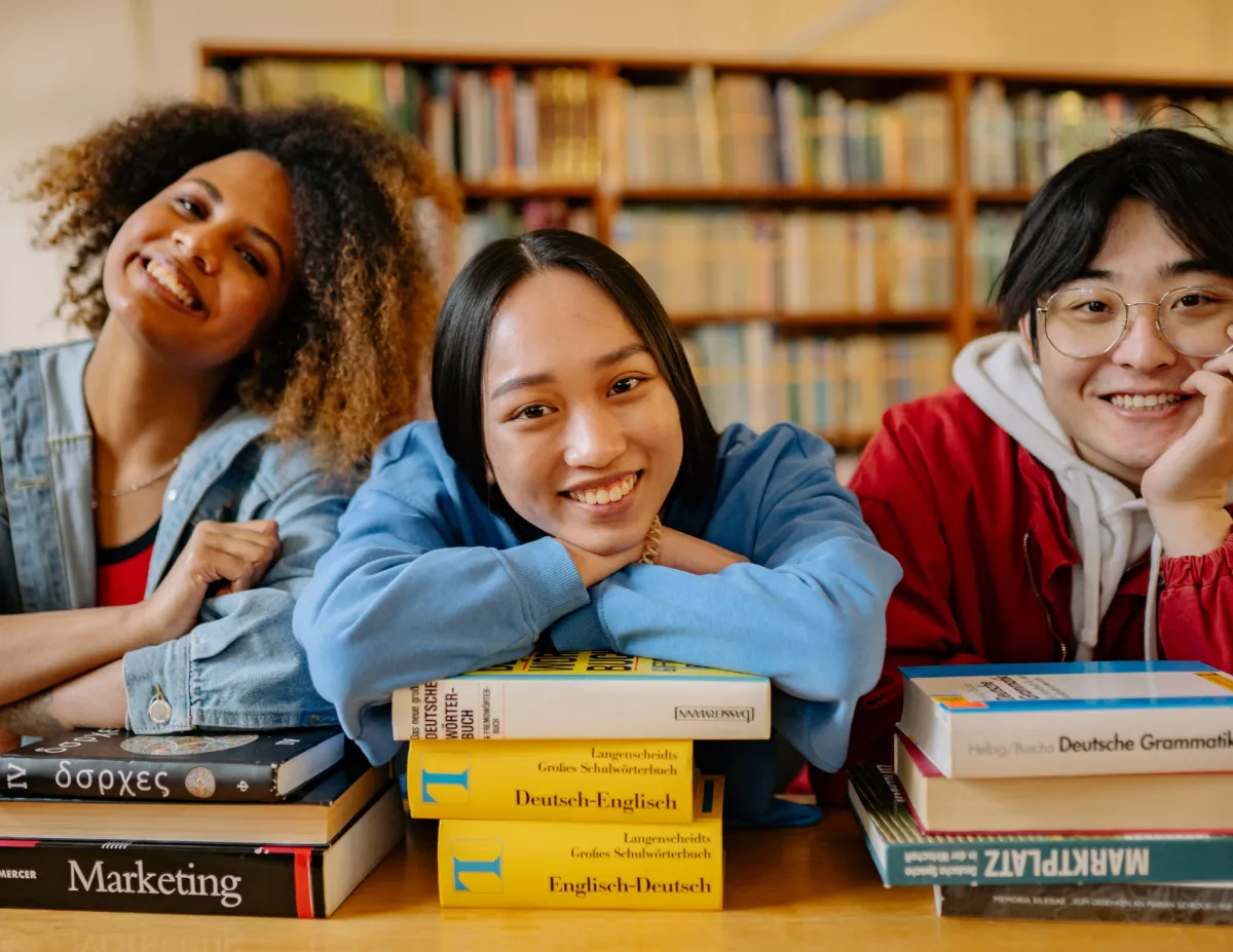 Studenten glimlachend op studieboeken aan een tafel
