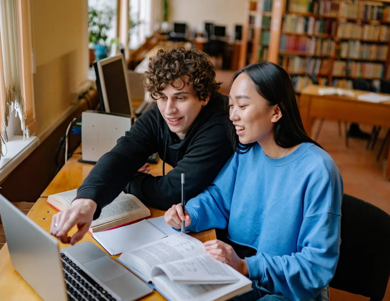 Jongen en meisje studeren achter een laptop met schriften en een pen