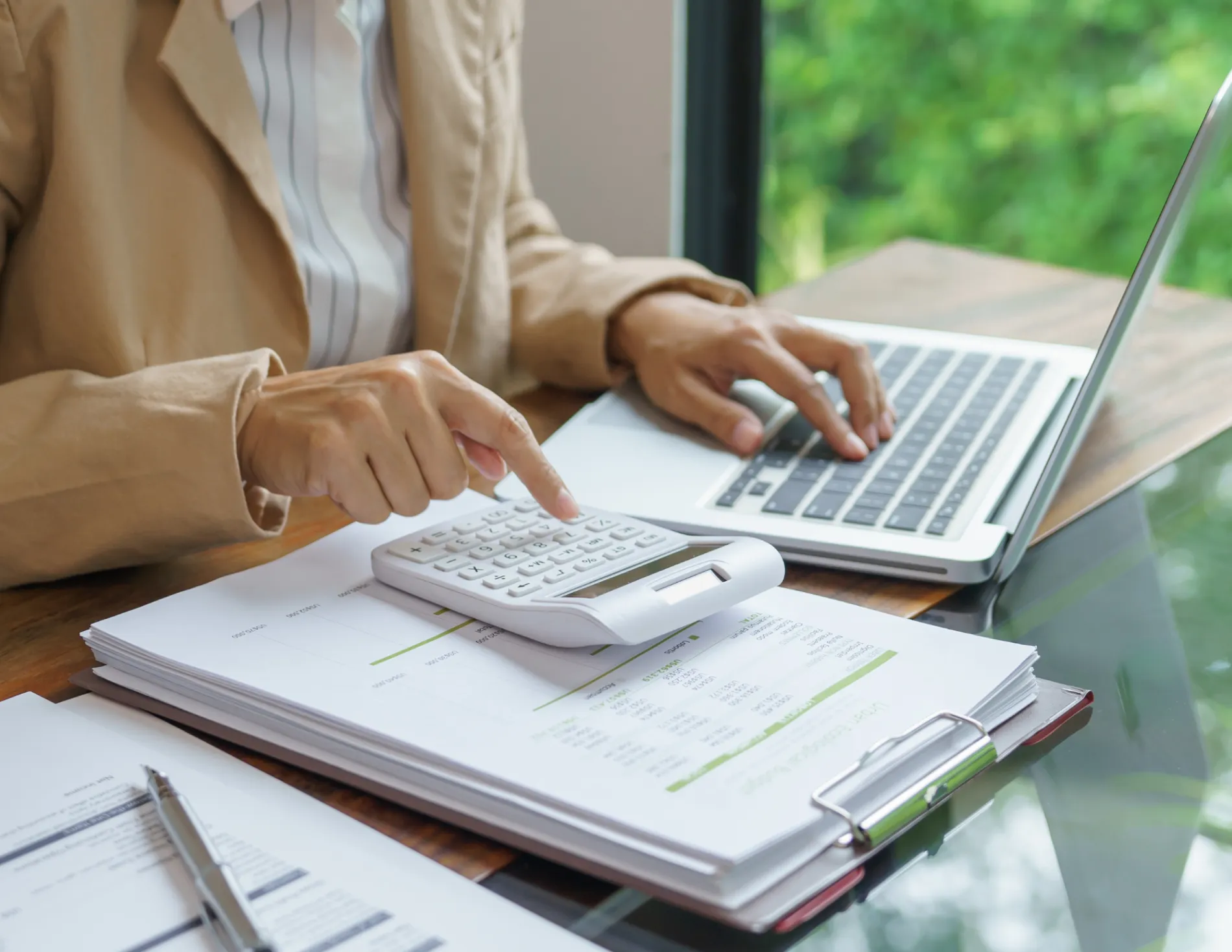 Persoon berekent kosten op rekenmachine en laptop