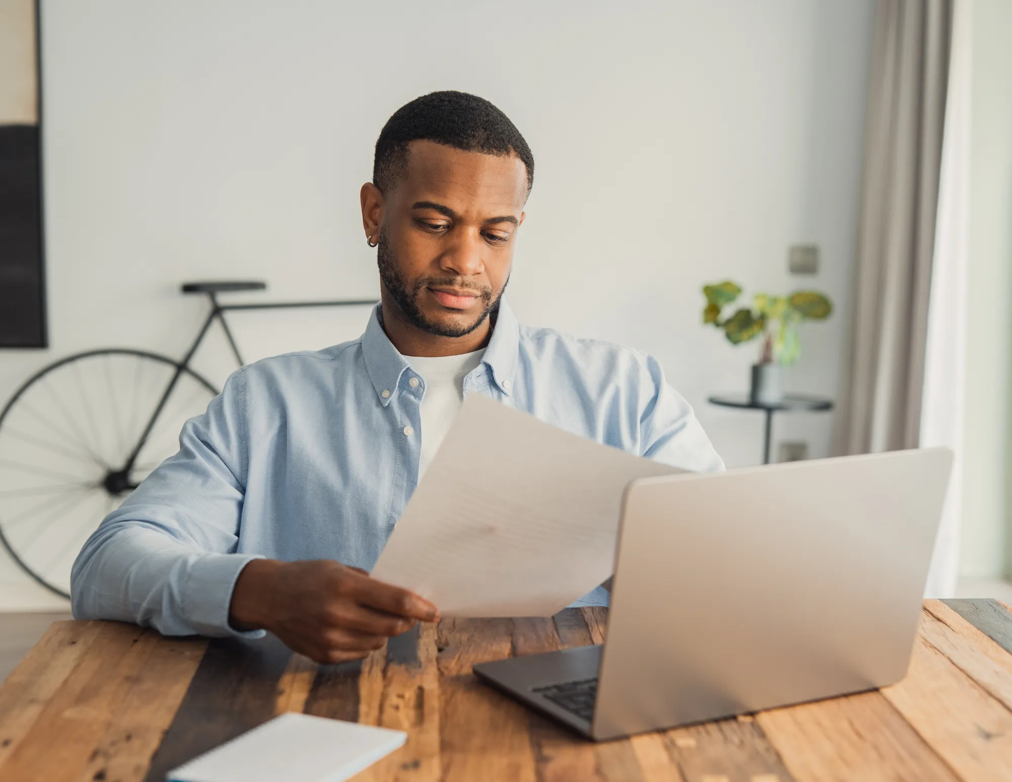 Man achter laptop met cv op papier