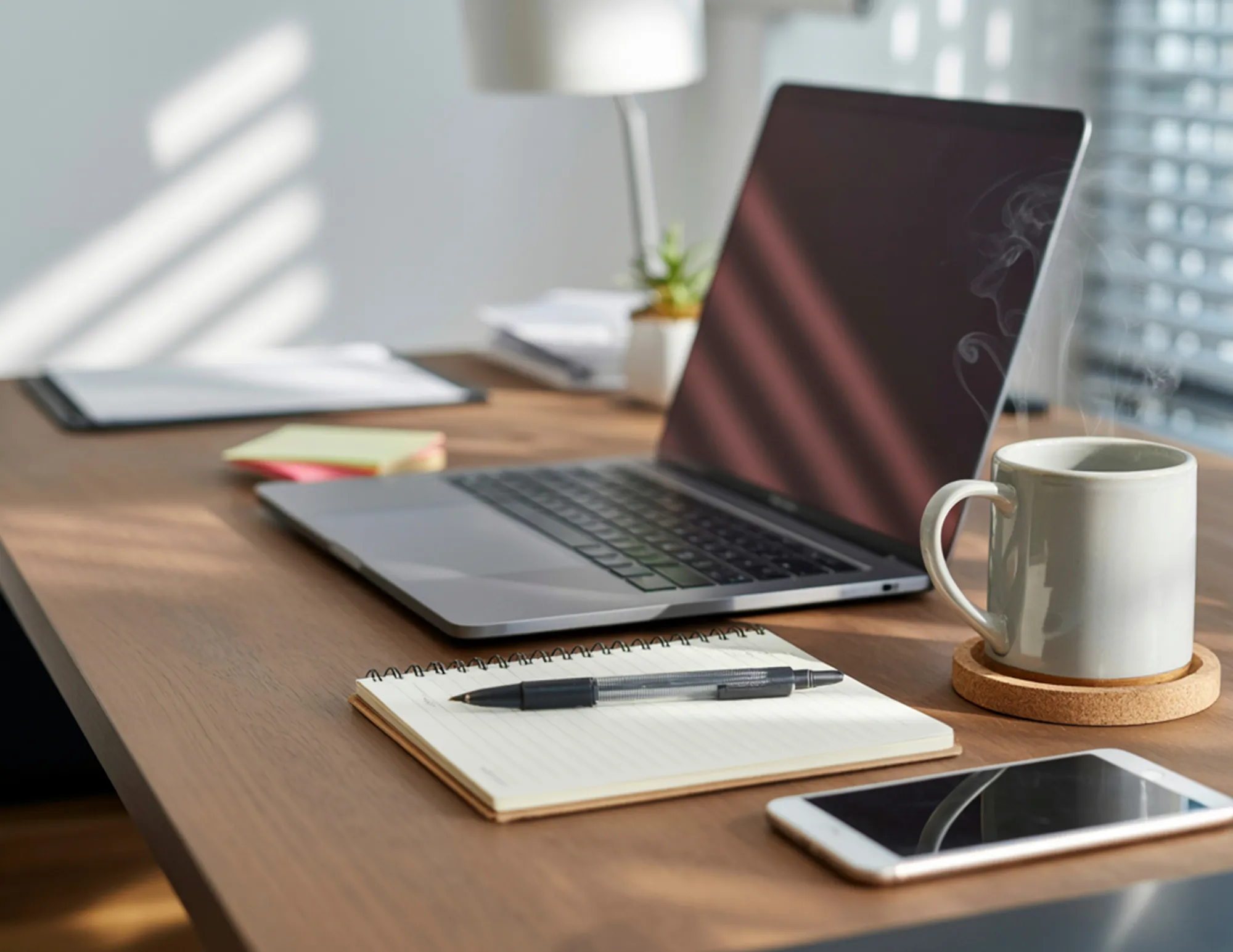 Bureau met een laptop, schrift, telefoon en mok