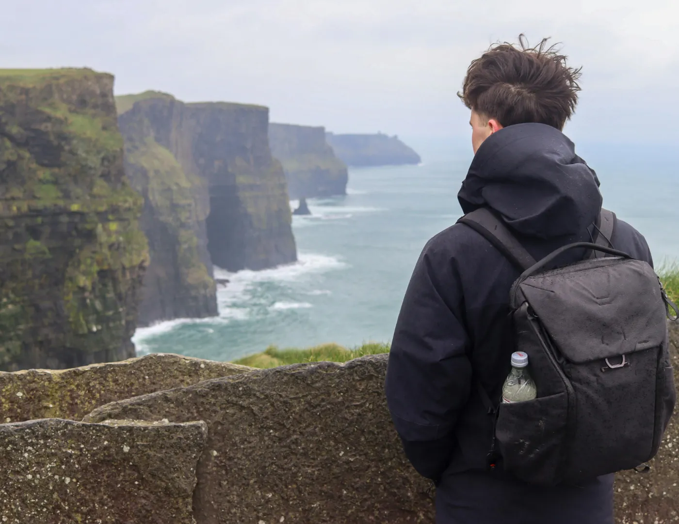 Jongen kijkt naar uitzicht met klif en de zee