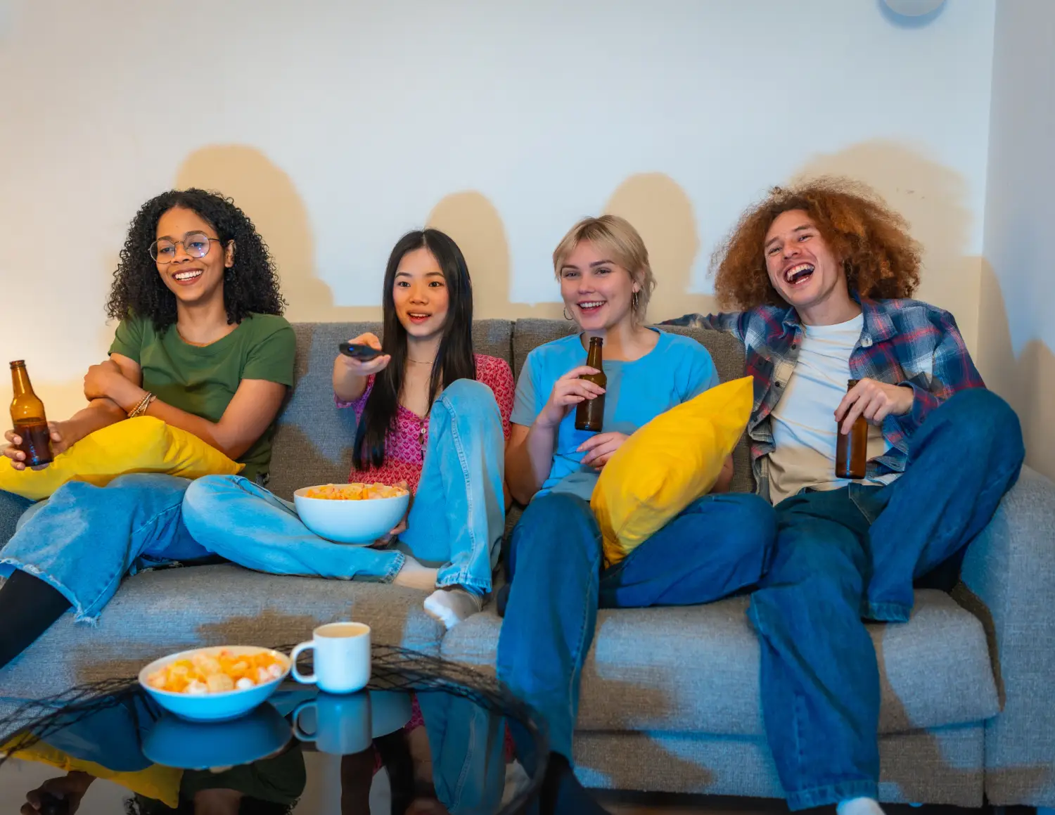 Vier huisgenoten samen op een bank met chips en een biertje