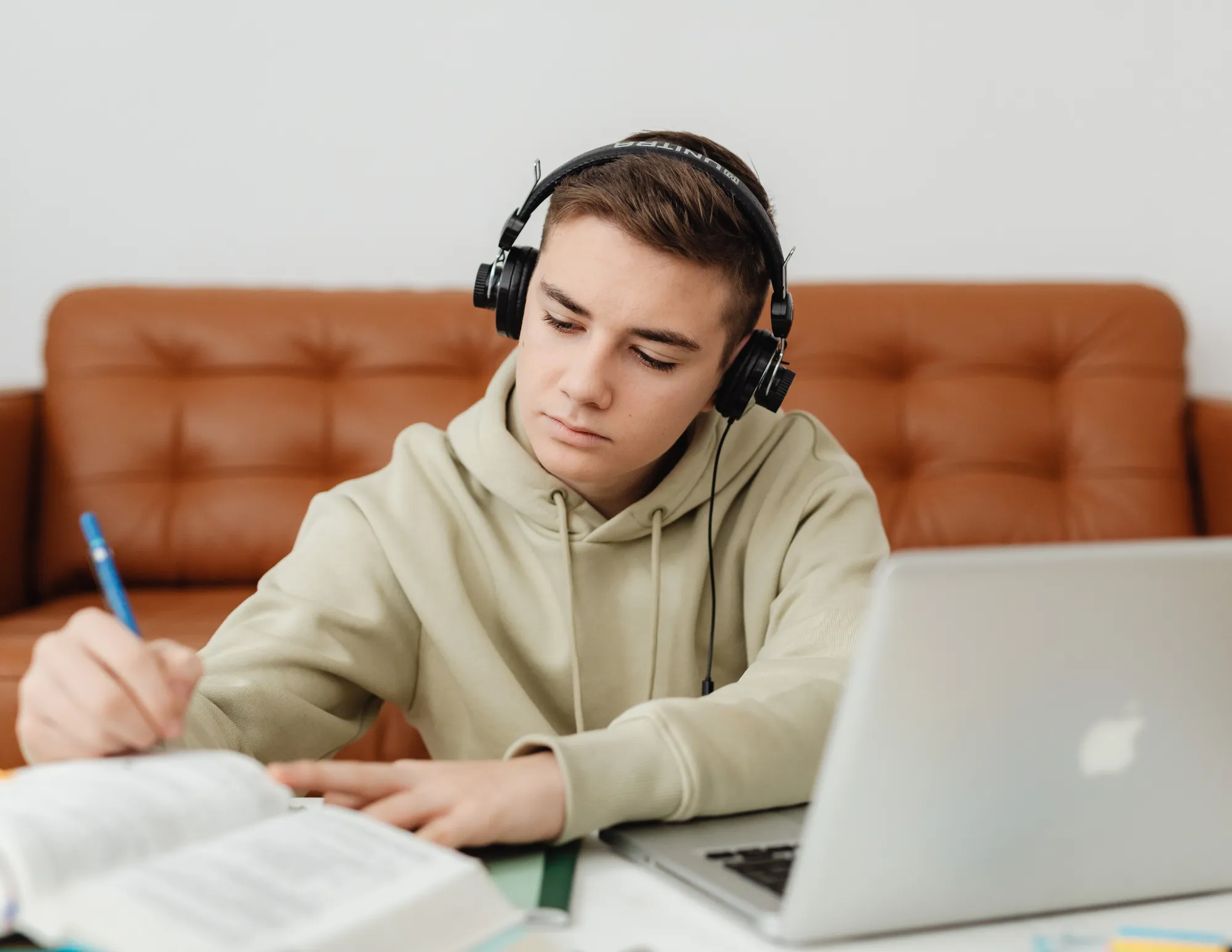 Jongen aan het studeren achter laptop en boek