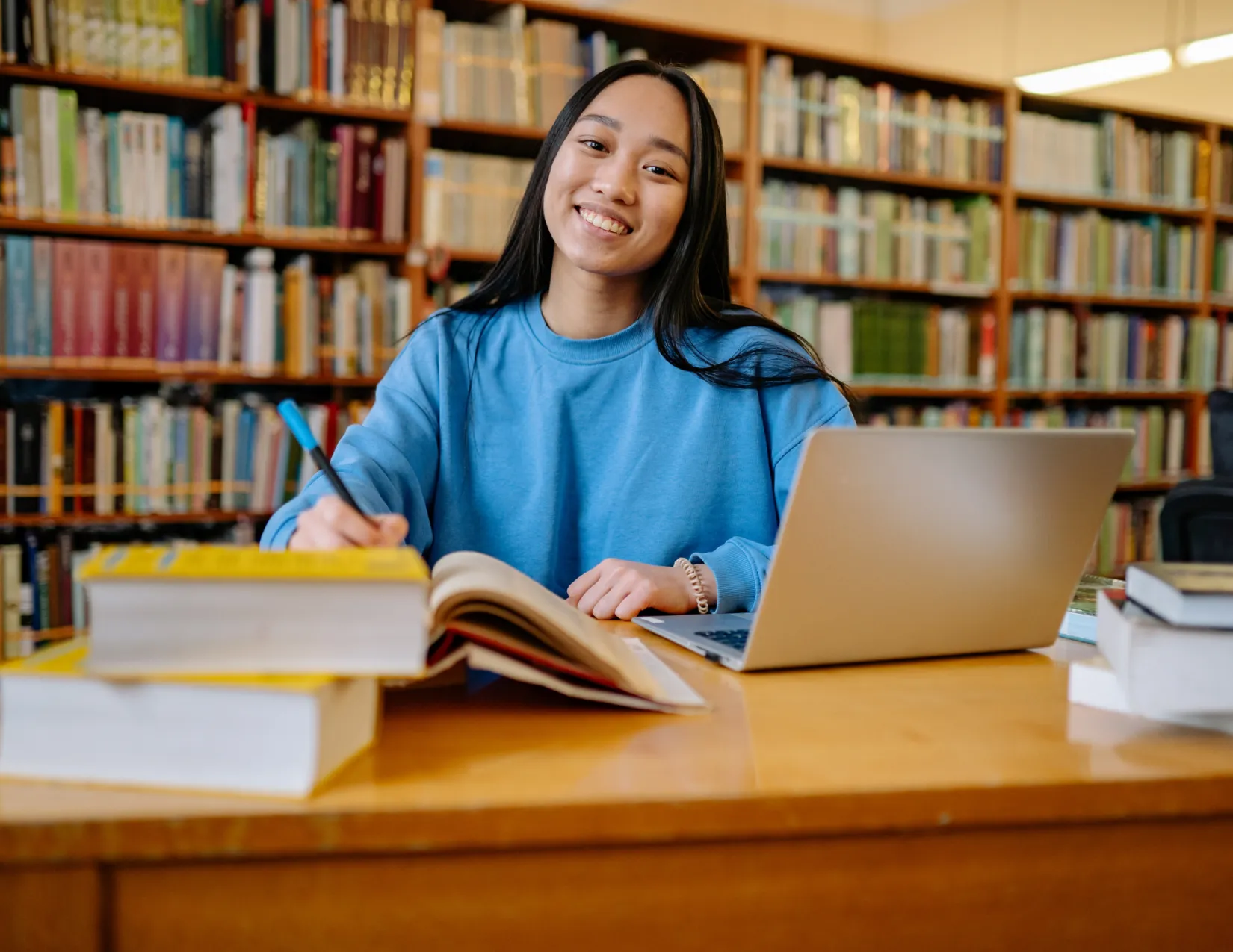 Vrouw die lacht aan het werk of studeren achter laptop en boeken